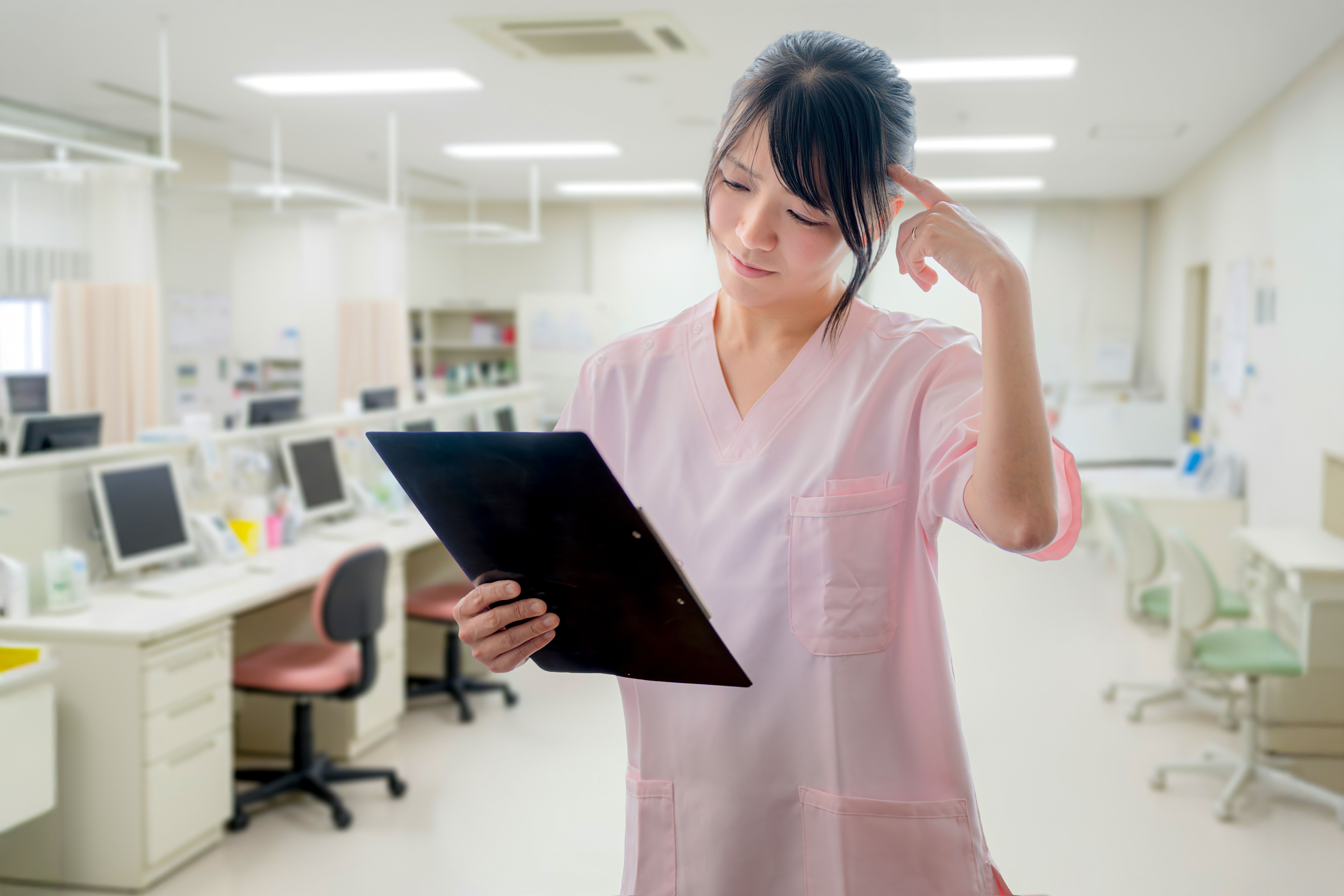 ナースステーションで業務に追われ疲れを感じる看護師のイメージ