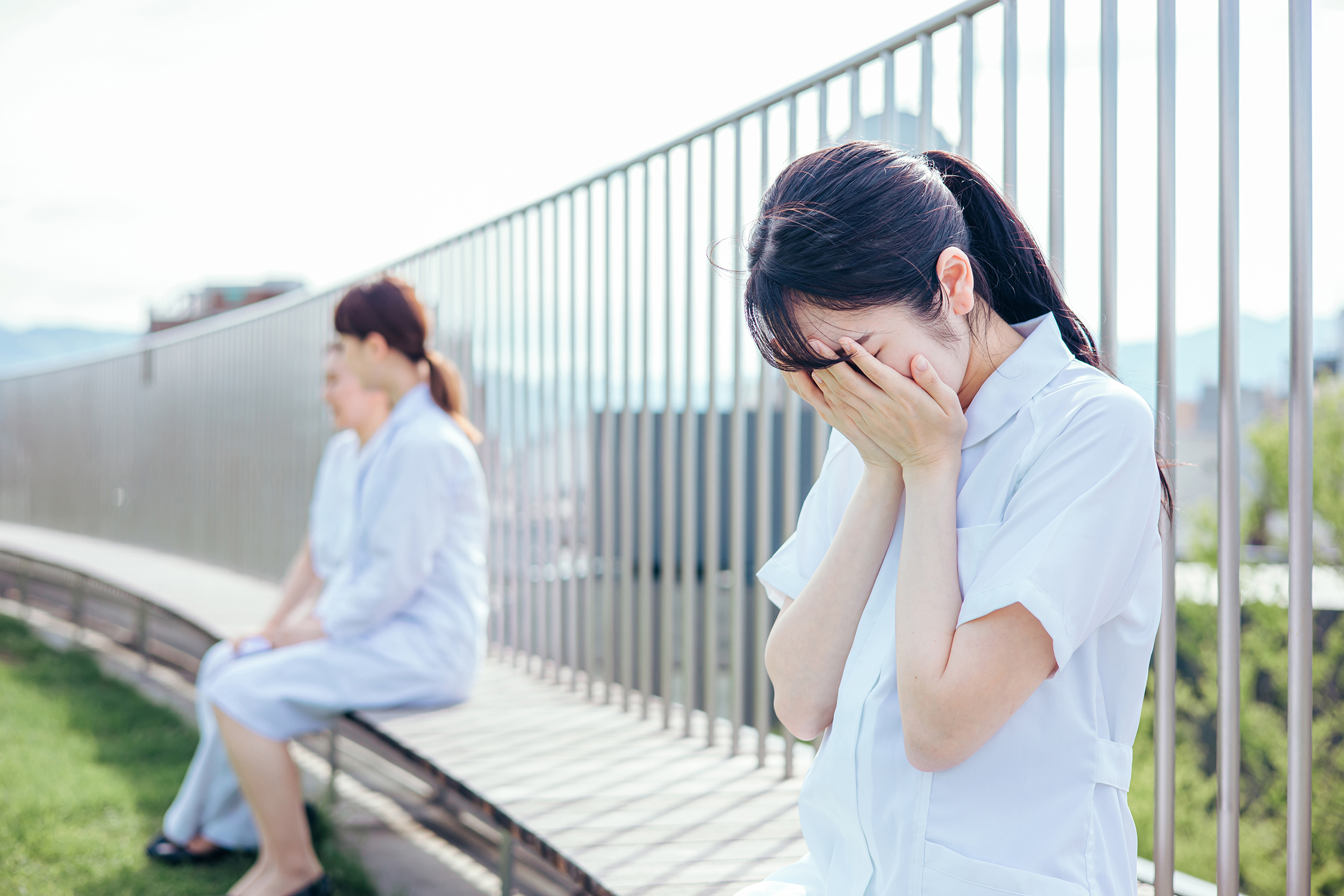 職場で気持ちが沈み顔を覆う看護師のイメージ